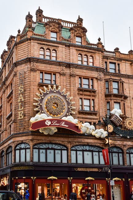 The exterior of a historic building in Knightsbridge decorated for the holiday season with large ornate gingerbread man and star ornaments, golden gears, snowflakes, and festive banners hanging along the facade. The building features a detailed stone facade with tall windows, a central domed tower, and decorative architectural elements. The scene is illuminated by soft natural daylight, highlighting the cleanliness and decorative details of the display, with no visible dirt or clutter. This image showcases the grandeur of the Harrods shopping destination, emphasizing its architectural beauty and seasonal decorations, as seen on the webpage of Cleaner Knightsbridge offering surface cleaning and deep cleaning services in the area.