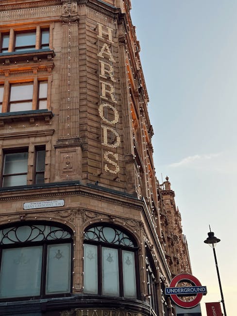 Close-up view of a historic red brick building in Knightsbridge featuring ornate architectural details such as decorative stonework, arched windows, and columns, with clear glass panes reflecting the 